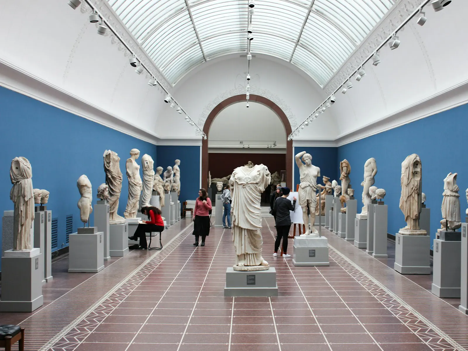 A museum hall with statues and visitors