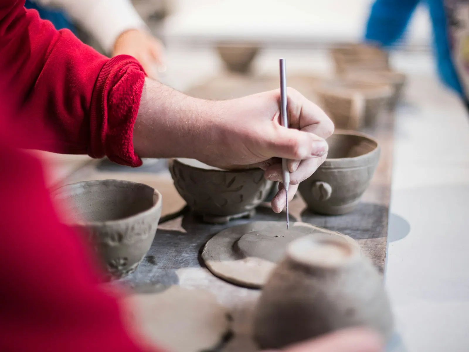 Hands painting pottery during a workshop